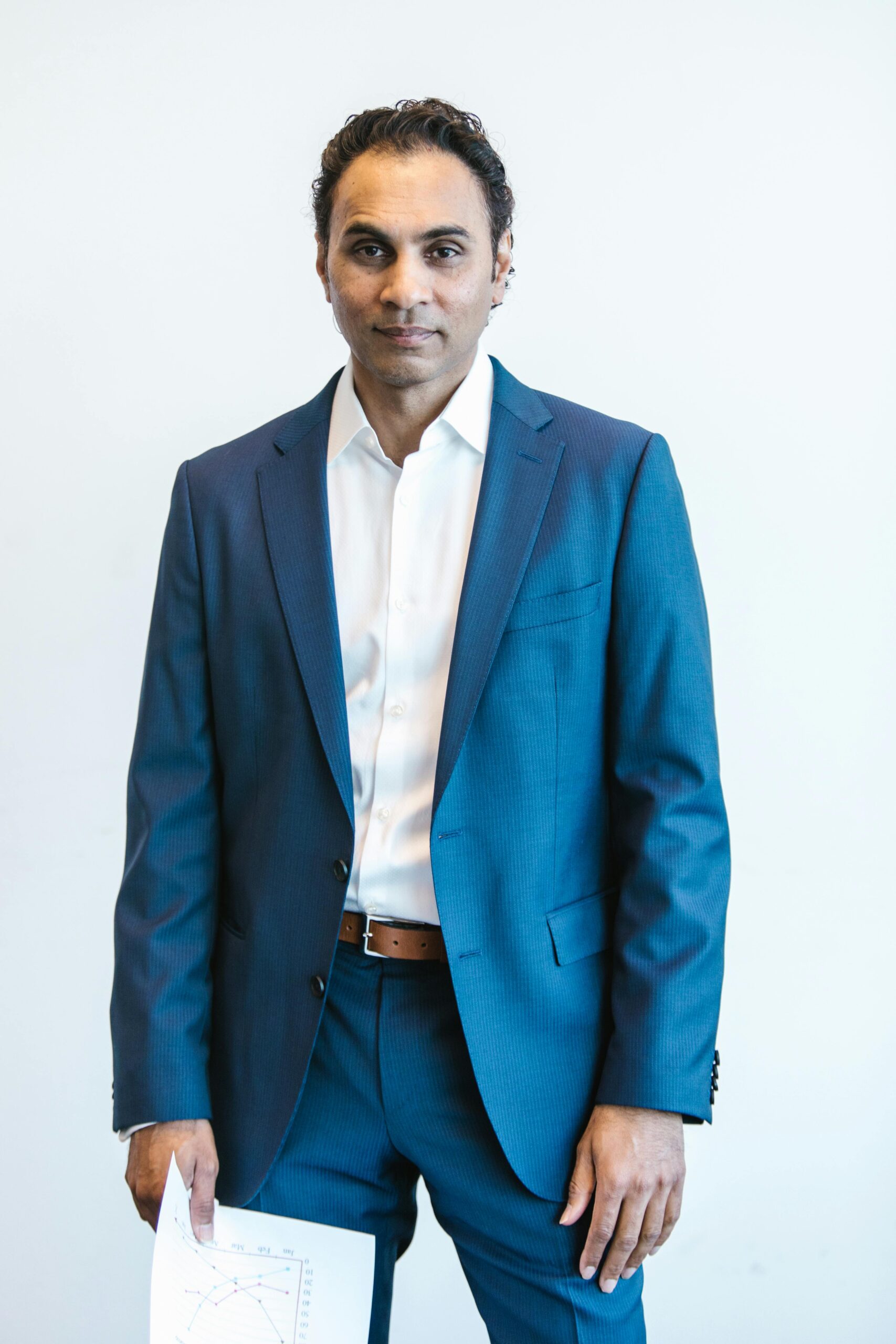 Portrait of a confident businessman holding papers in formal attire inside an office